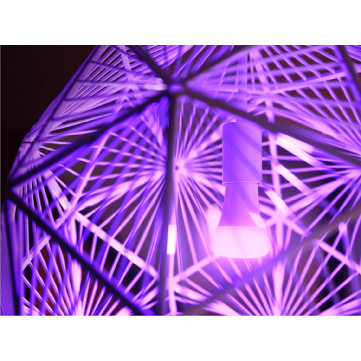 Primo piano di un moderno apparecchio di illuminazione geometrica con luce viola che brilla attraverso la sua struttura.