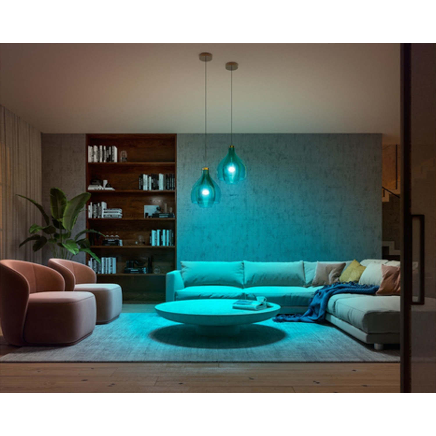 Soggiorno con illuminazione ambientale blu, divano, poltrone, tavolino, librerie e una pianta.