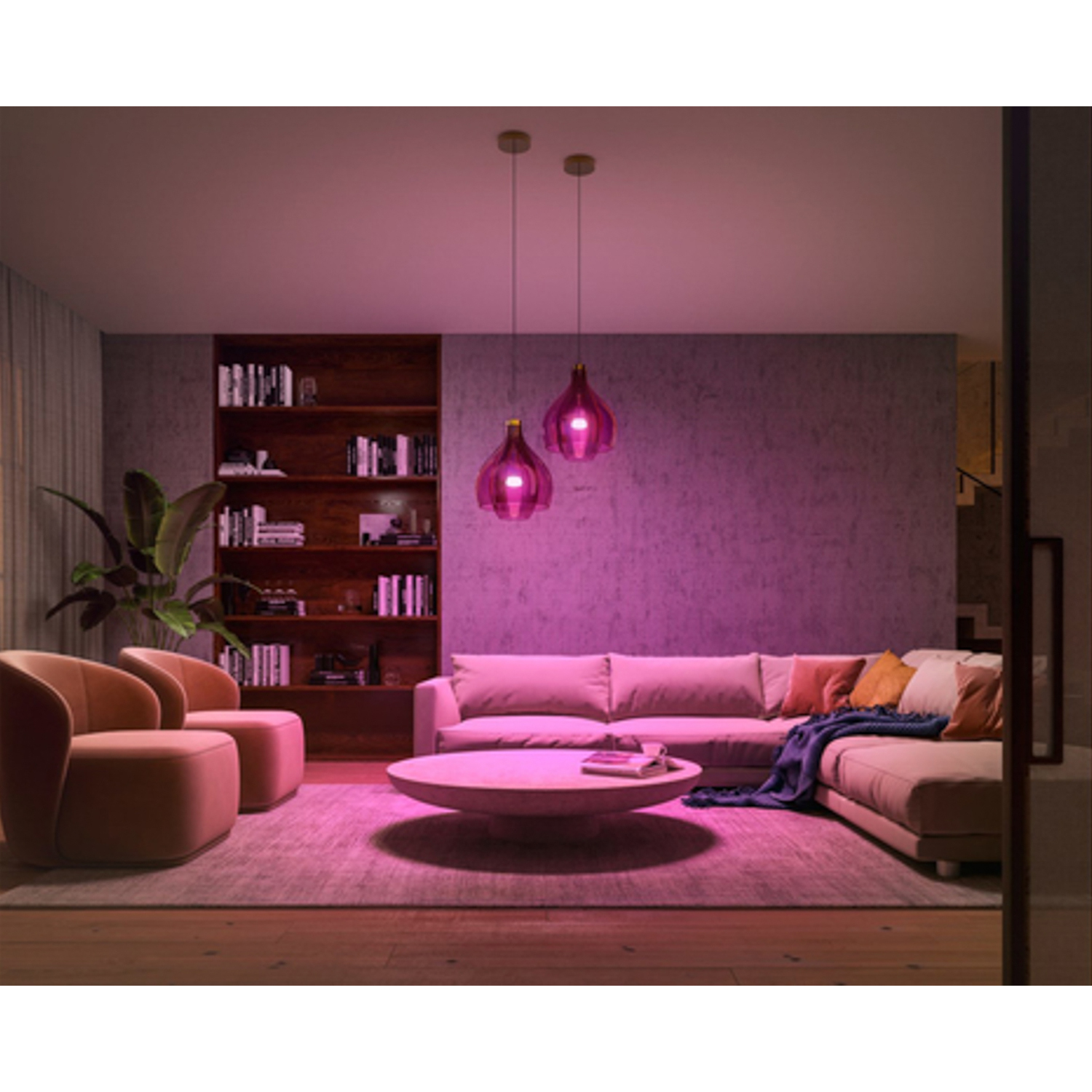 Un soggiorno con luce rosa. C'è un divano, poltrone, un tavolino e una libreria.