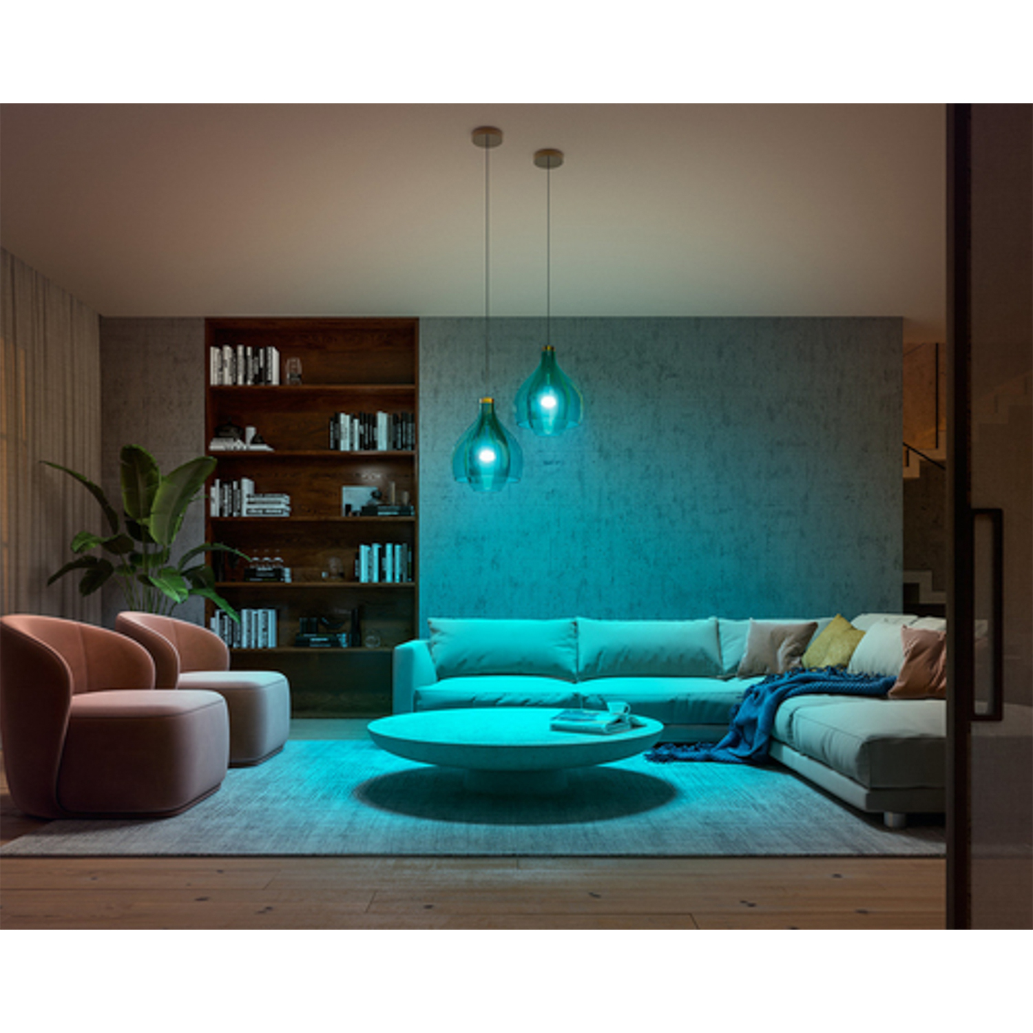 Soggiorno con illuminazione ambientale blu acqua. Due lampade, divano, libri e una grande pianta visibili.