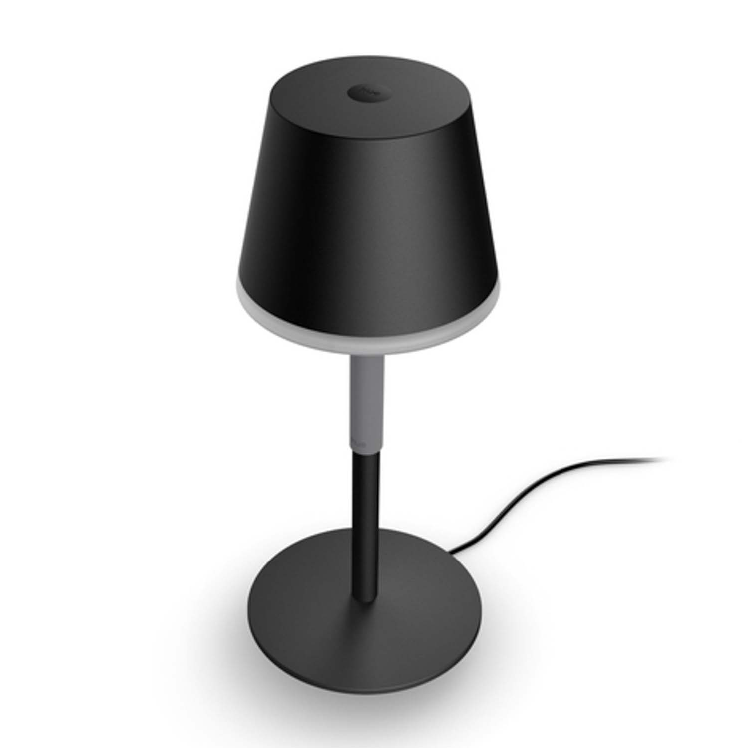 Una lampada da tavolo nera con paralume nero e base rotonda. È su una superficie bianca.