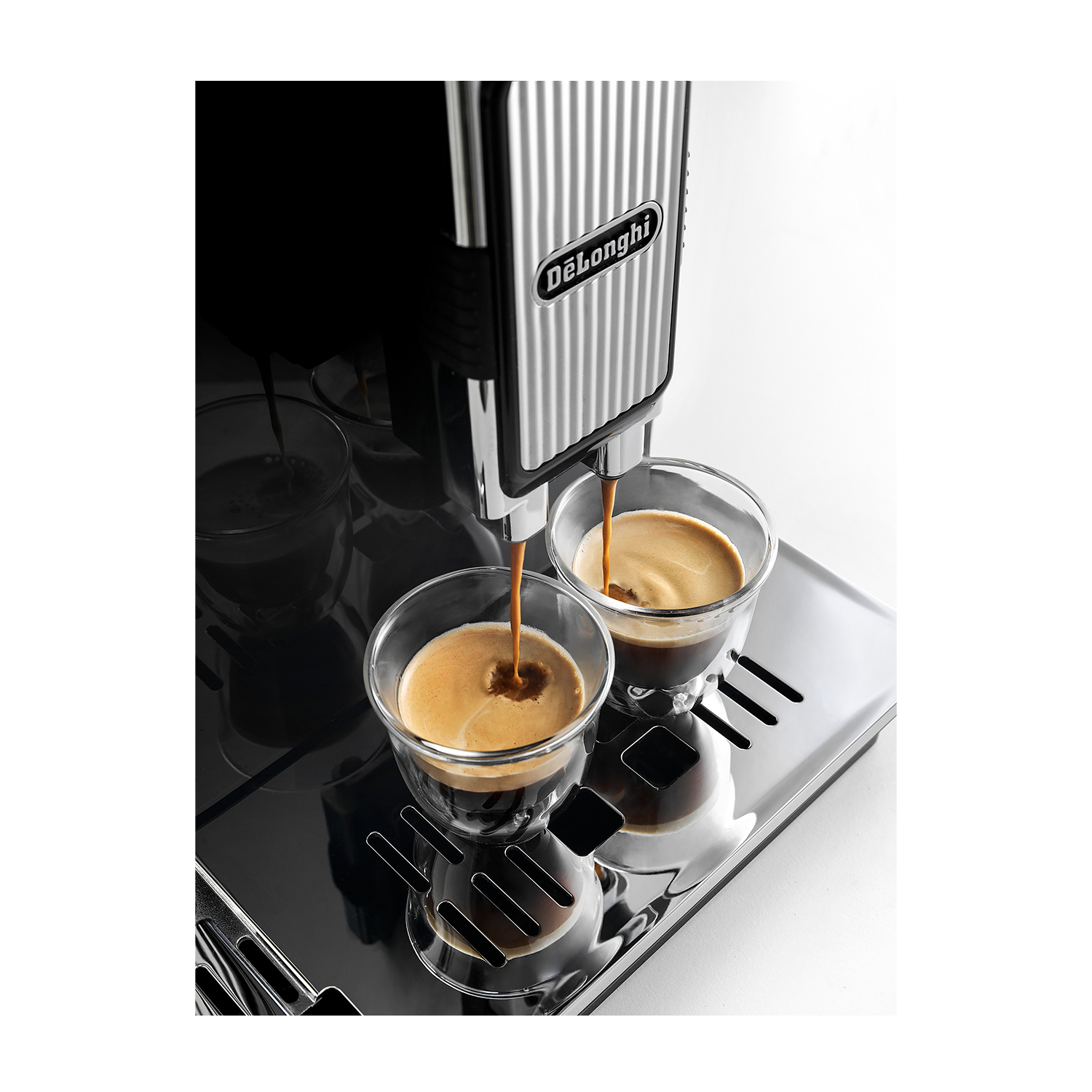Macchina per espresso che versa caffè. Due bicchieri con caffè. Vassoio d'argento su sfondo bianco.