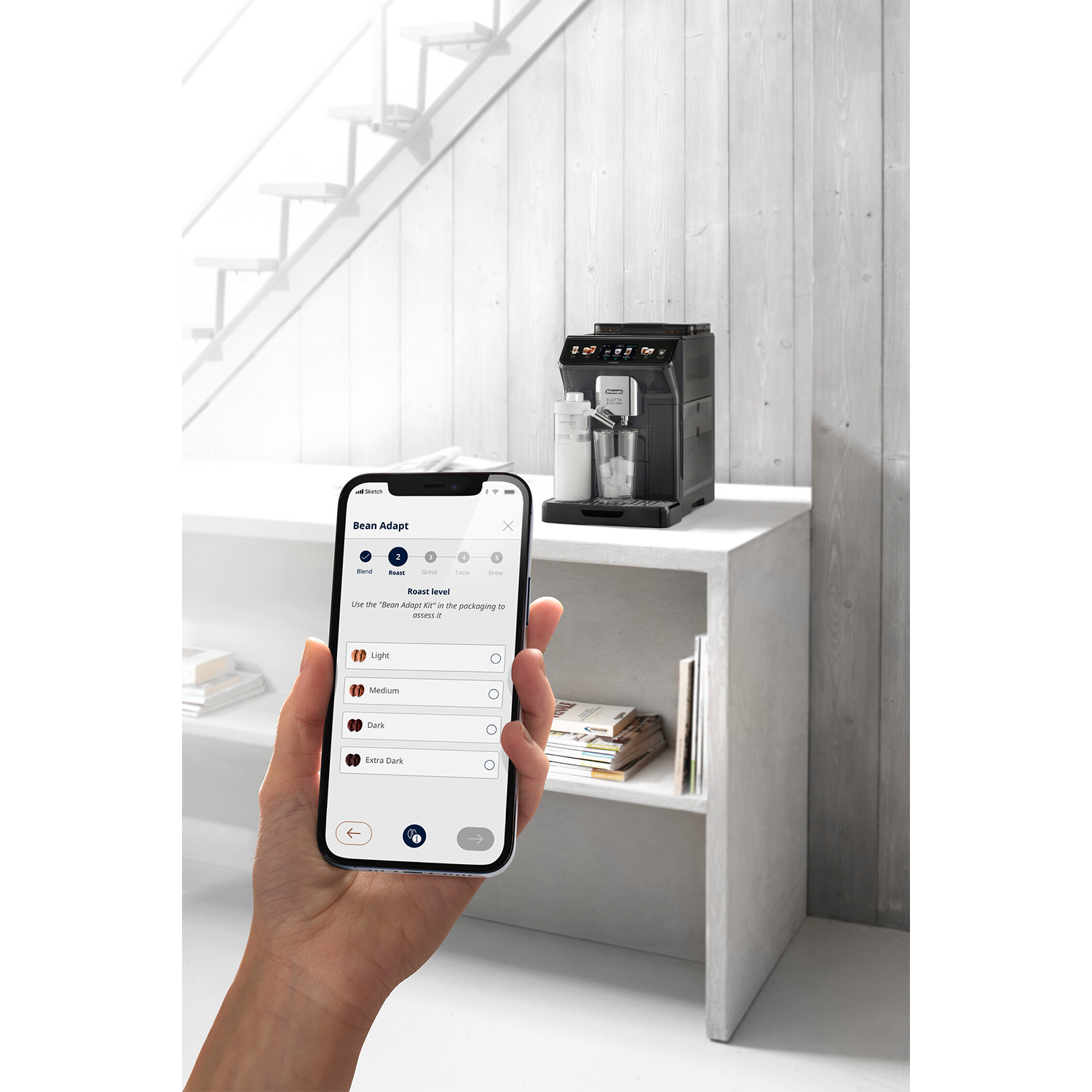 Persona usa telefono, macchina caffè su mensola.