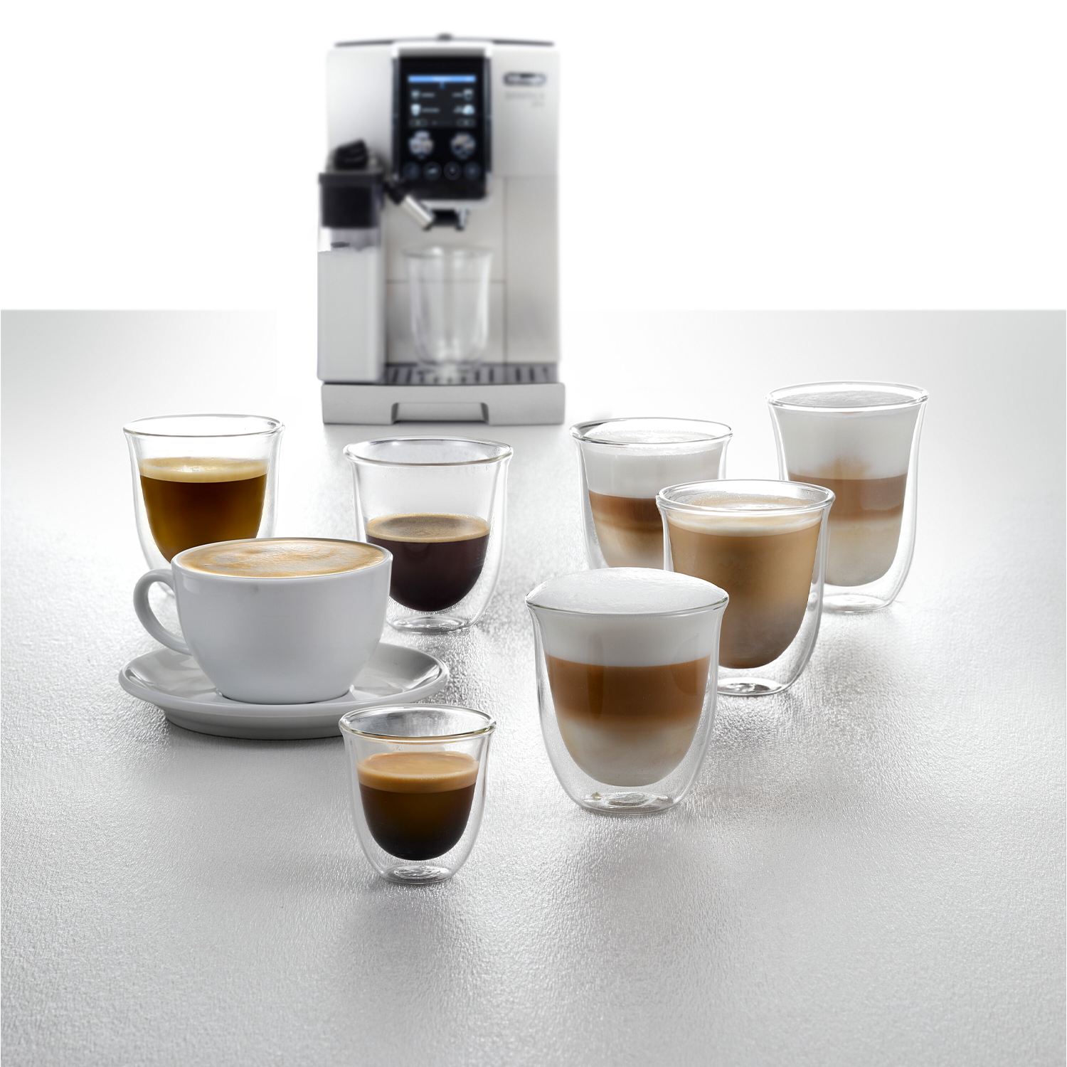 Diverse bevande al caffè in bicchieri di vetro, con una macchina da caffè sullo sfondo.
