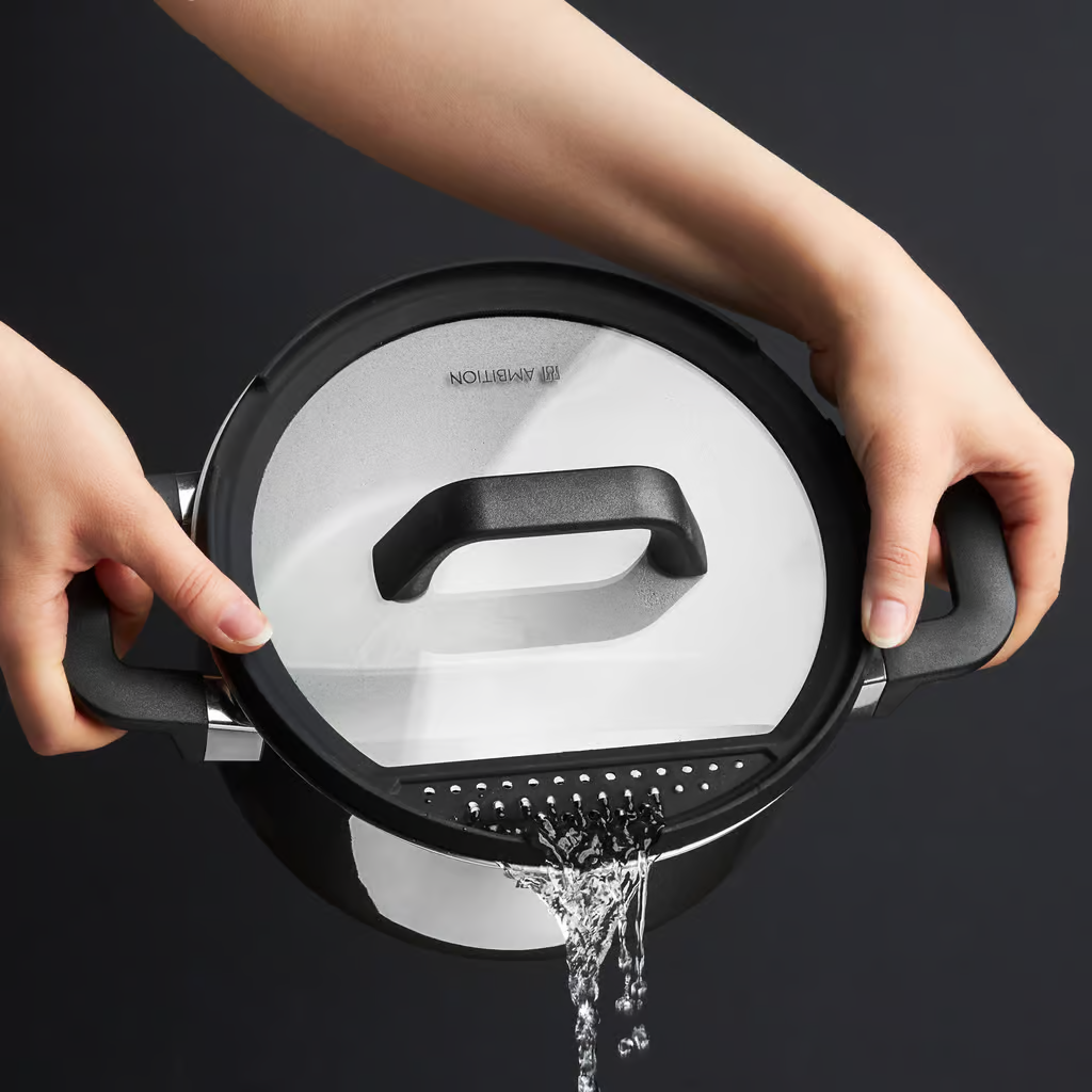 Dłonie trzymają garnek, wylewając wodę przez pokrywkę z sitkiem, na ciemnym tle.