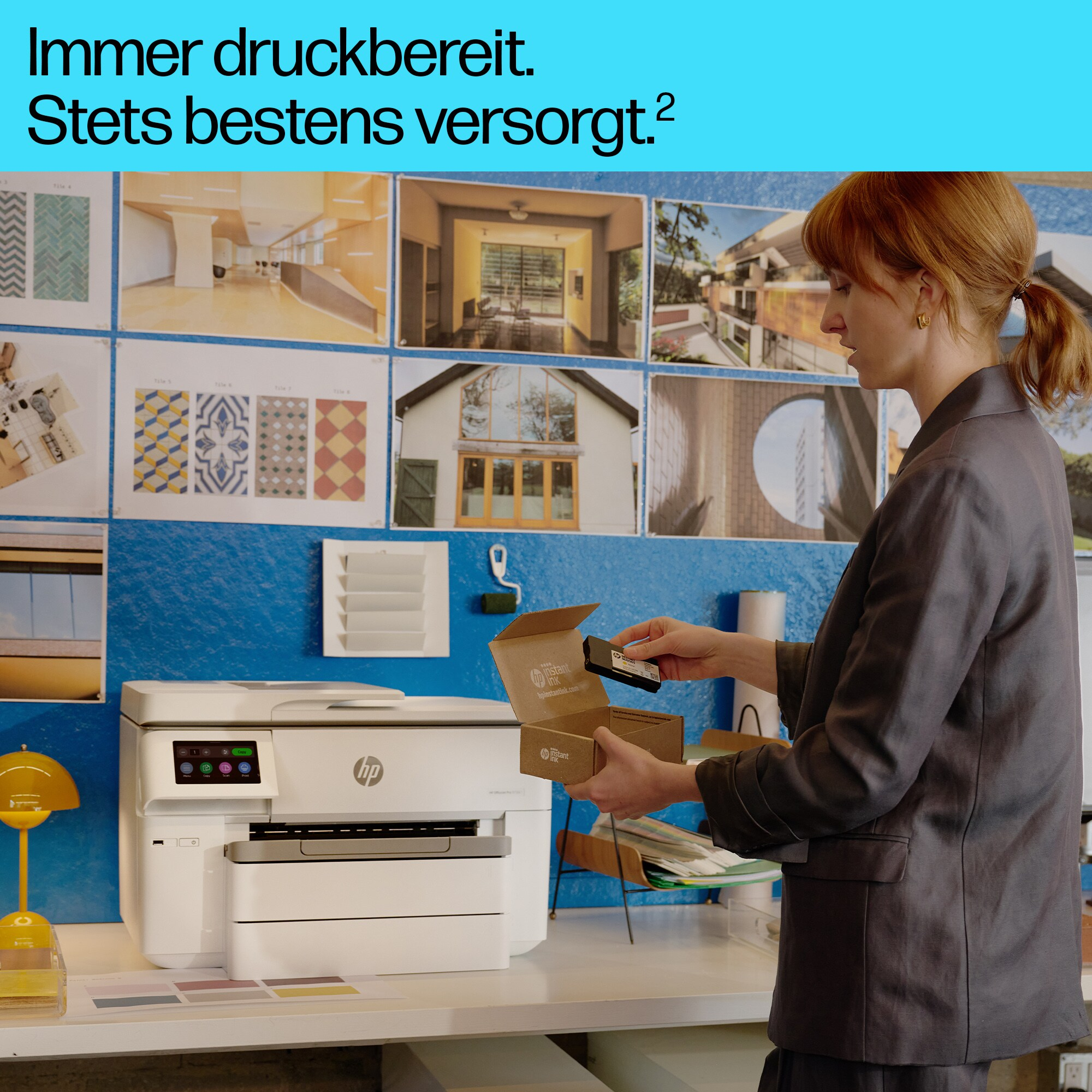 Frau packt Tintenpatronen neben einem Drucker mit Text. Büroumgebung mit Blaupausen.