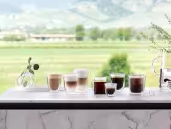 Filiżanki kawy na białym stole z widokiem na zielone pole.