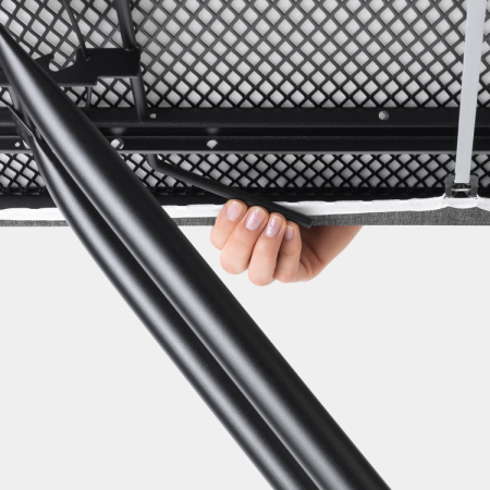 Die Hand einer Person berührt eine Metalloberfläche unter einem Tisch. Schwarze Beine.
