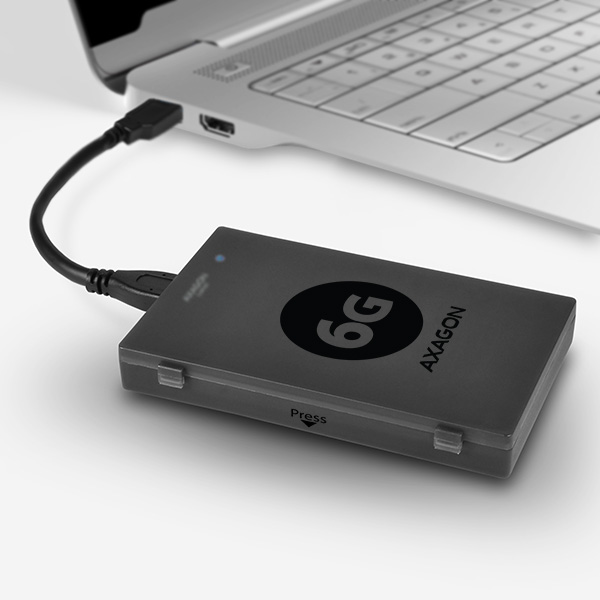 Fekete Axagon külső merevlemez laptophoz csatlakoztatva USB-kábellel. Fehér felületen.