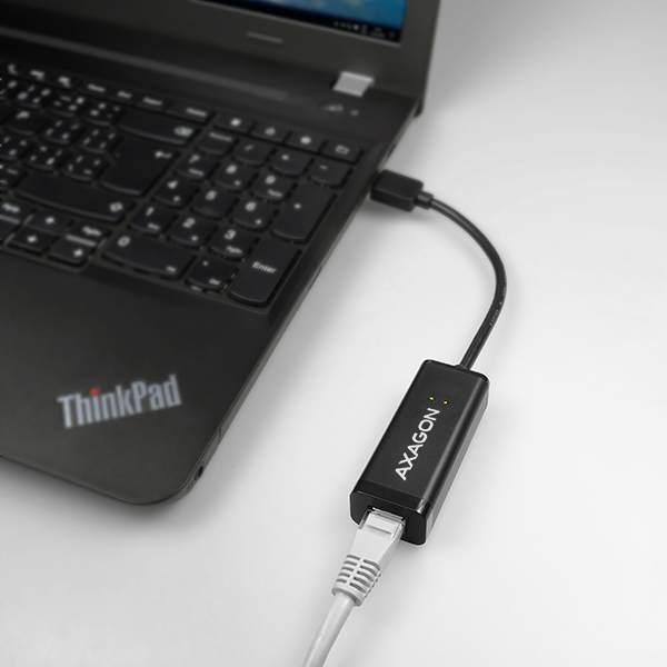 Egy fekete ThinkPad laptop egy fekete AXAGON adapterhez csatlakozik rövid kábellel.