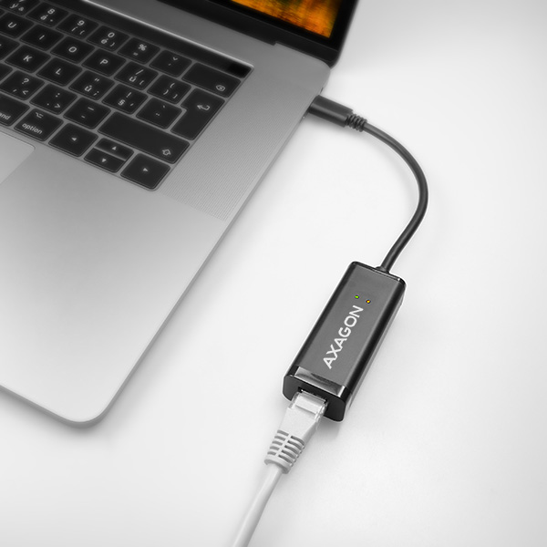 Laptop egy Ethernet adapterrel, ami kábellel van csatlakoztatva. Az adapter fekete, AXAGON felirattal.