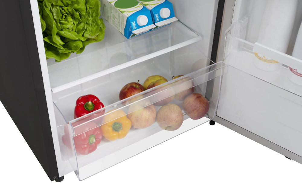 A fridge drawer with apples and peppers, lettuce and juice cartons in the background.