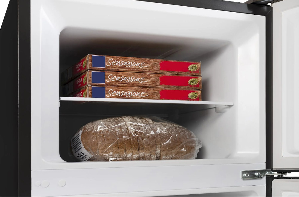 Open fridge with frozen pizzas and a loaf of bread. Black fridge, white interior.
