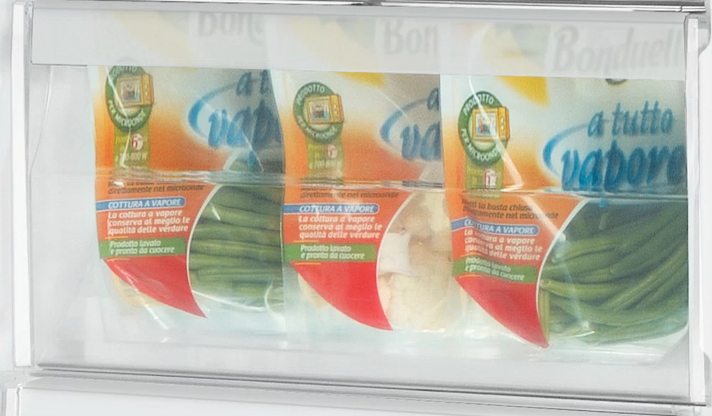 Három csomag zöldbab egy átlátszó hűtőfiókban.