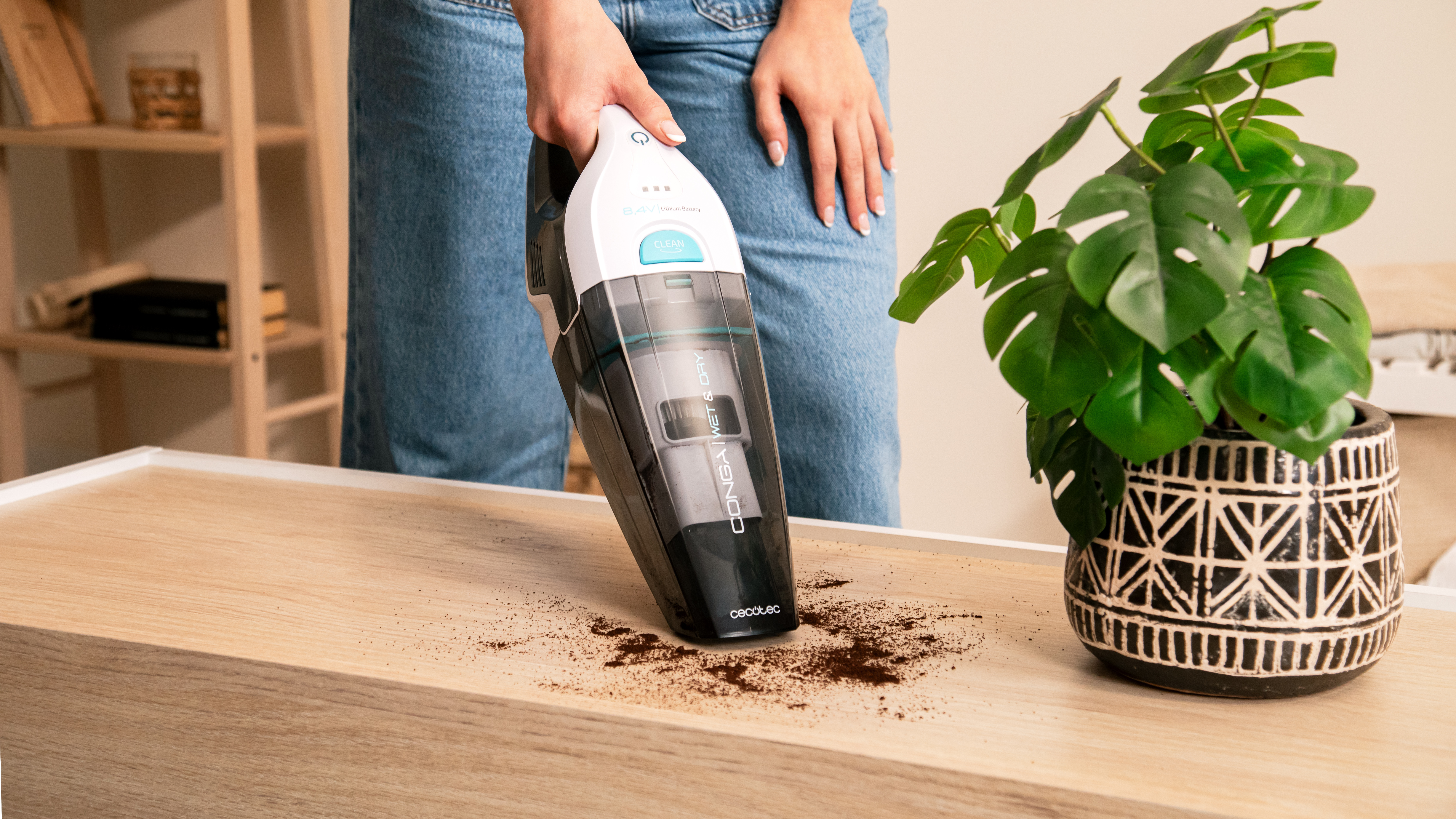 Una persona usa una aspiradora de mano para limpiar café derramado.