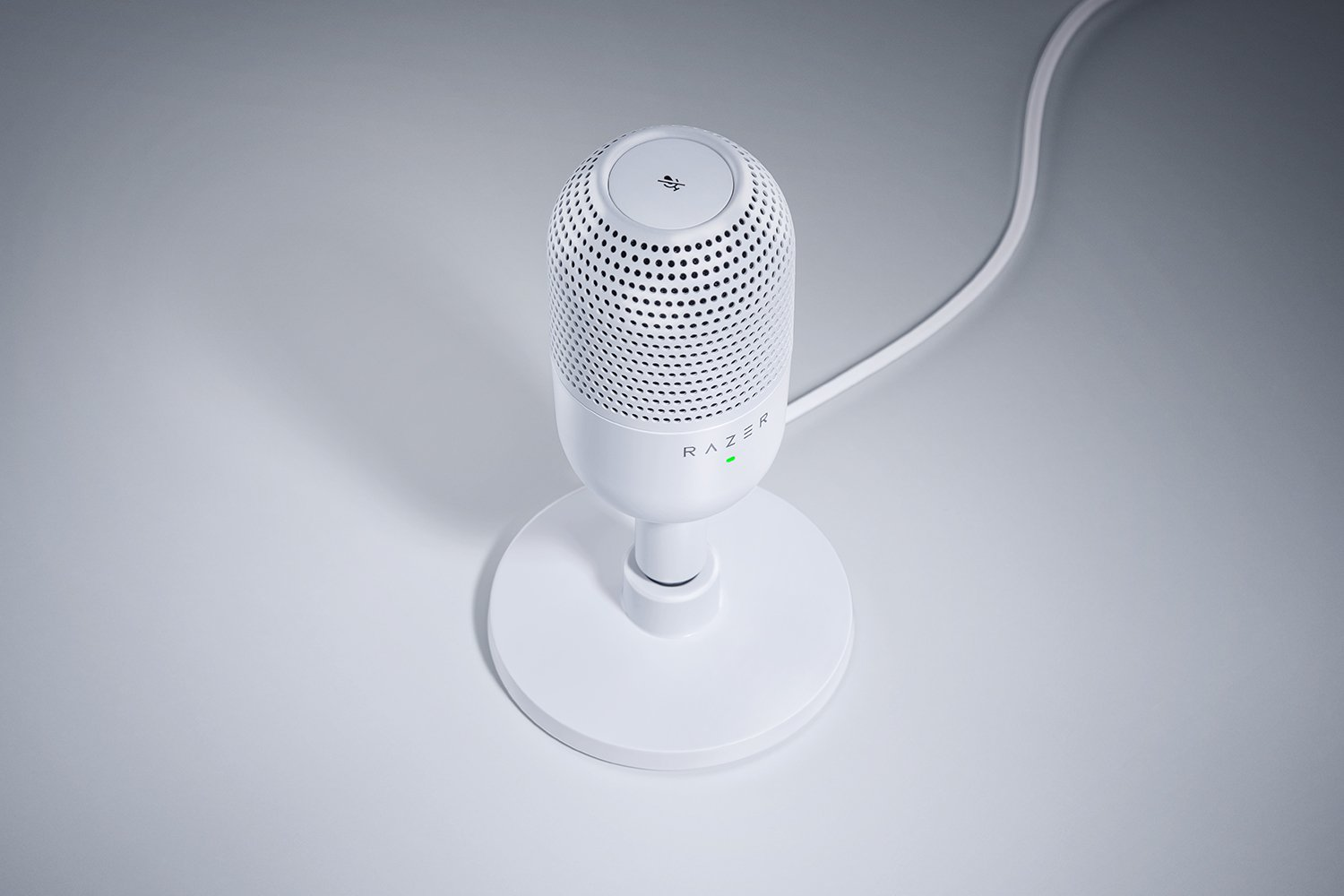 Weißes Razer-Mikrofon auf einem Ständer mit grünem Licht, auf einer hellen Oberfläche.