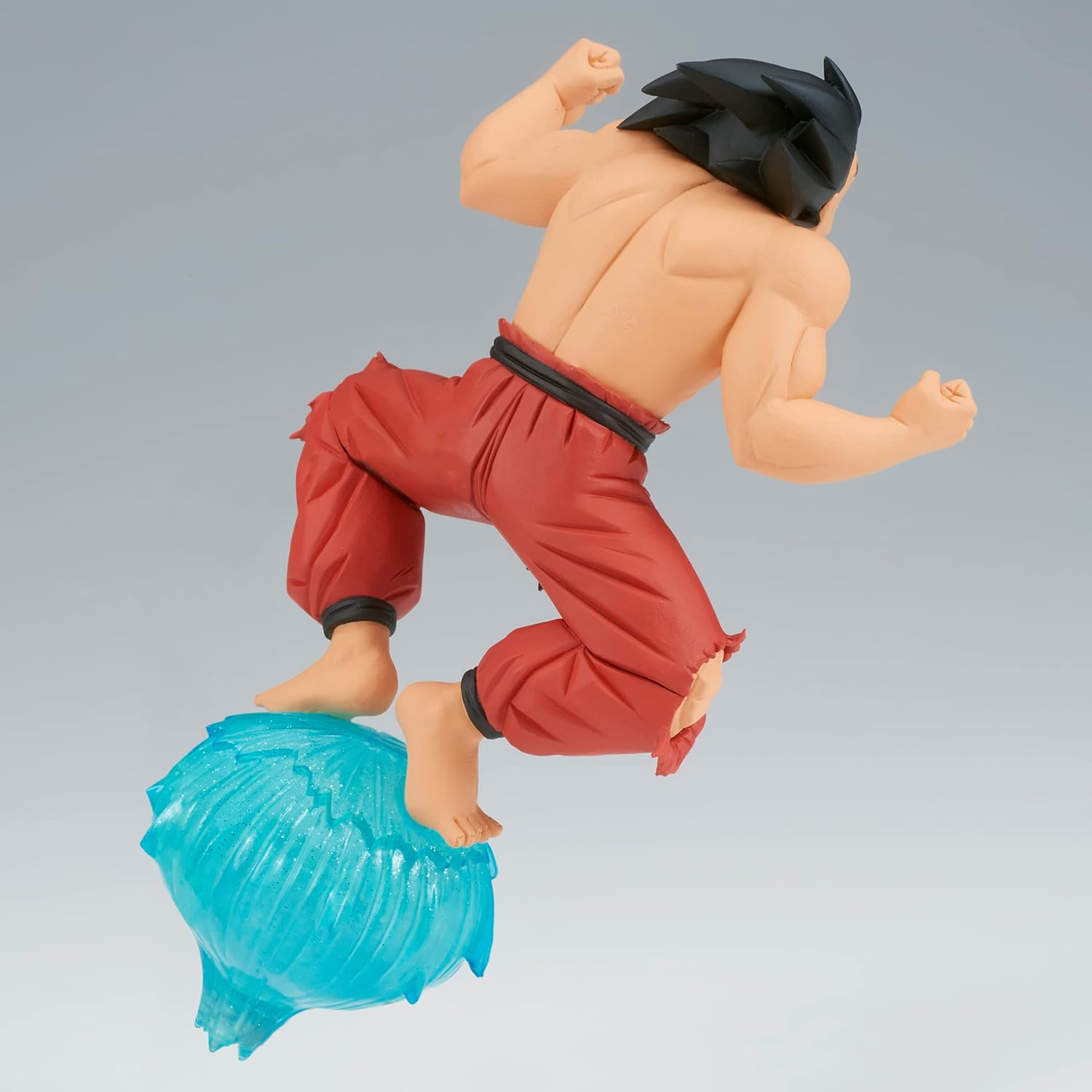 Figura de un hombre musculoso con pantalones rojos rotos, en el aire, saltando sobre una bola de energía azul.