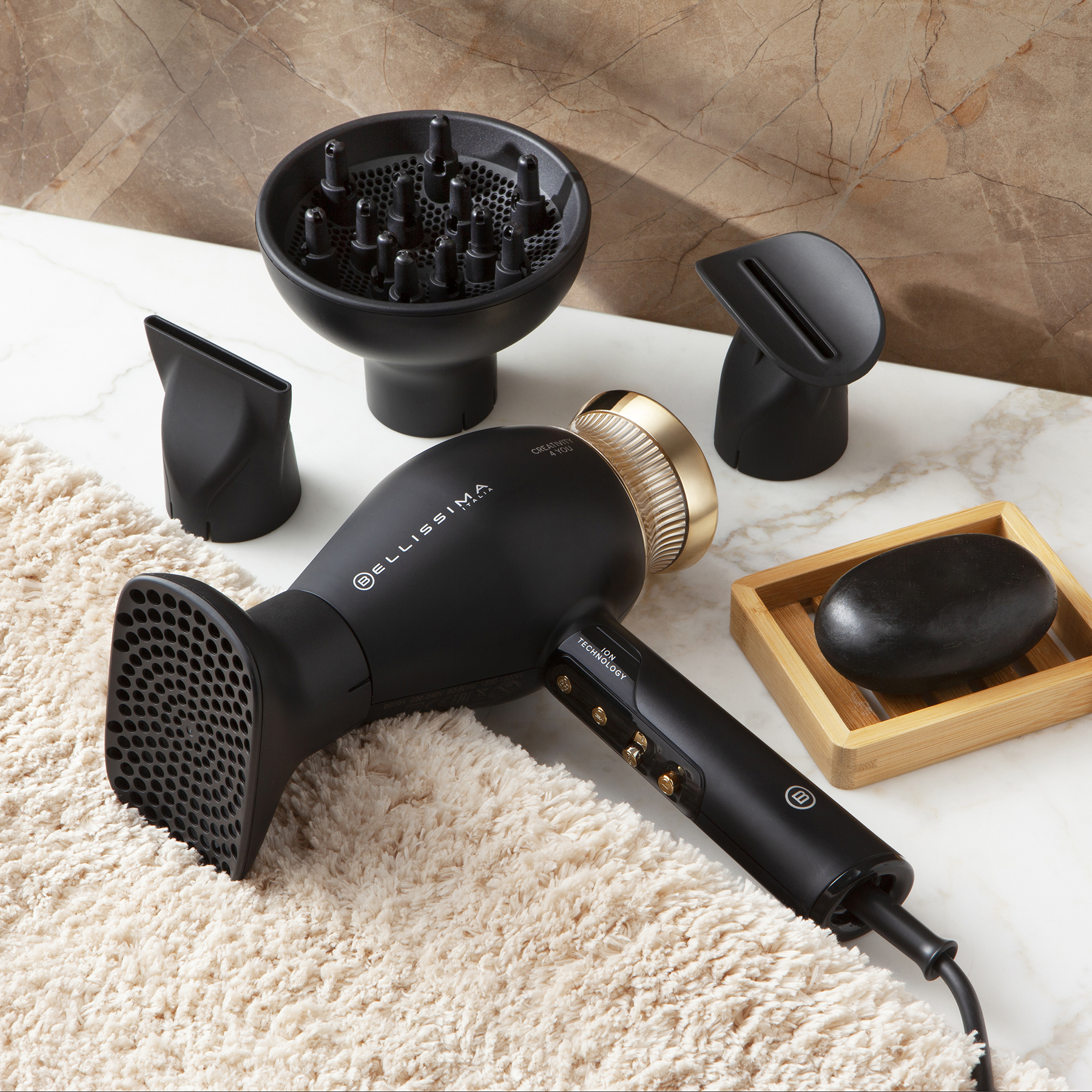 Un sèche-cheveux noir et doré avec diffuseur et embouts sur une surface blanche.