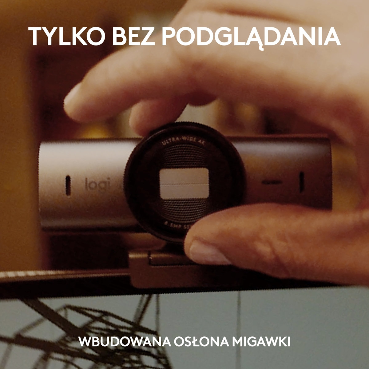 Dłoń trzyma kamerę internetową. Tekst mówi "Wbudowana migawka". Zdjęcie jest zbliżeniem.