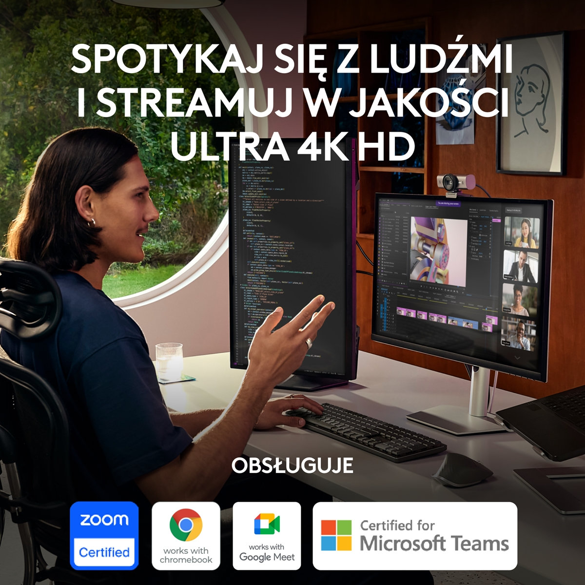 Mężczyzna pracuje przy biurku z dwoma monitorami, klawiaturą i kamerą internetową. Tło to pokój.
