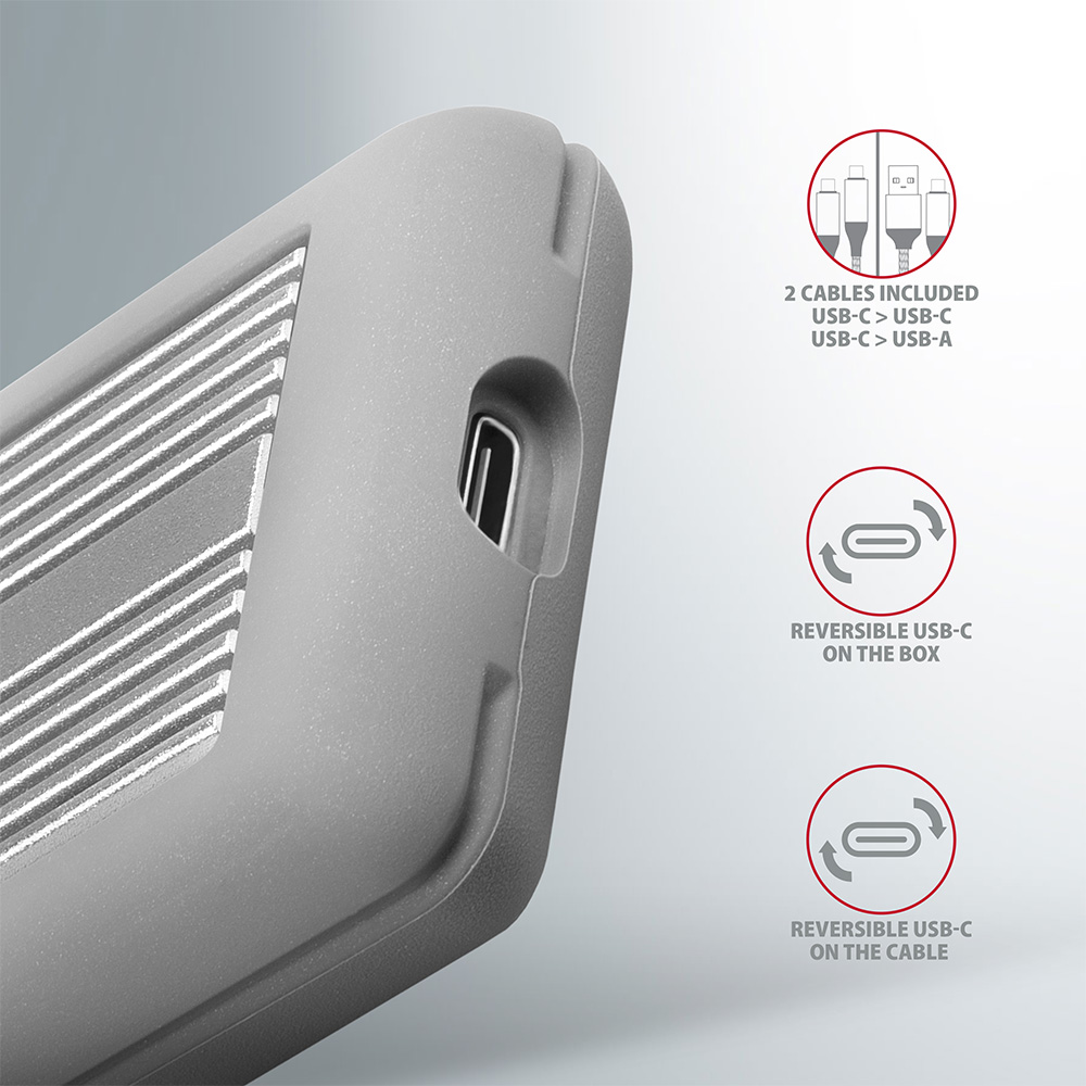 Közelkép egy szürke eszközről USB-porttal és szöveges címkékkel. Kábelek mellékelve.