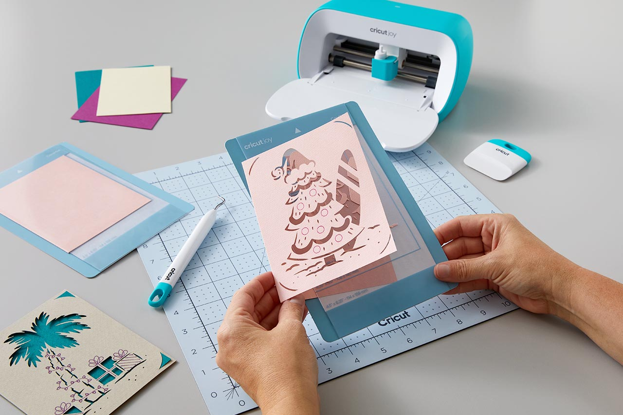 Hände schneiden Papierkunst mit einer Cricut Joy Maschine und verschiedenen Papierformen.