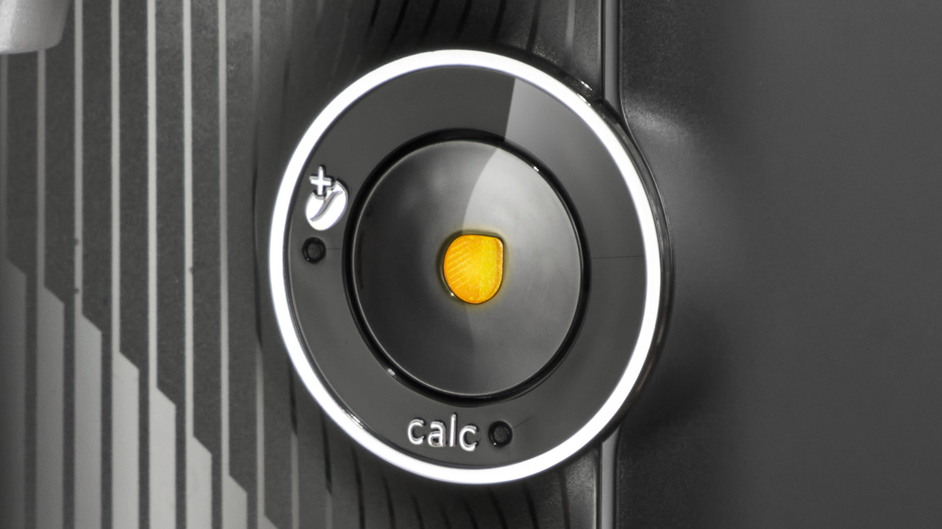 Nahaufnahme eines schwarzen Bedienfelds mit rundem Knopf und Text 'calc'.