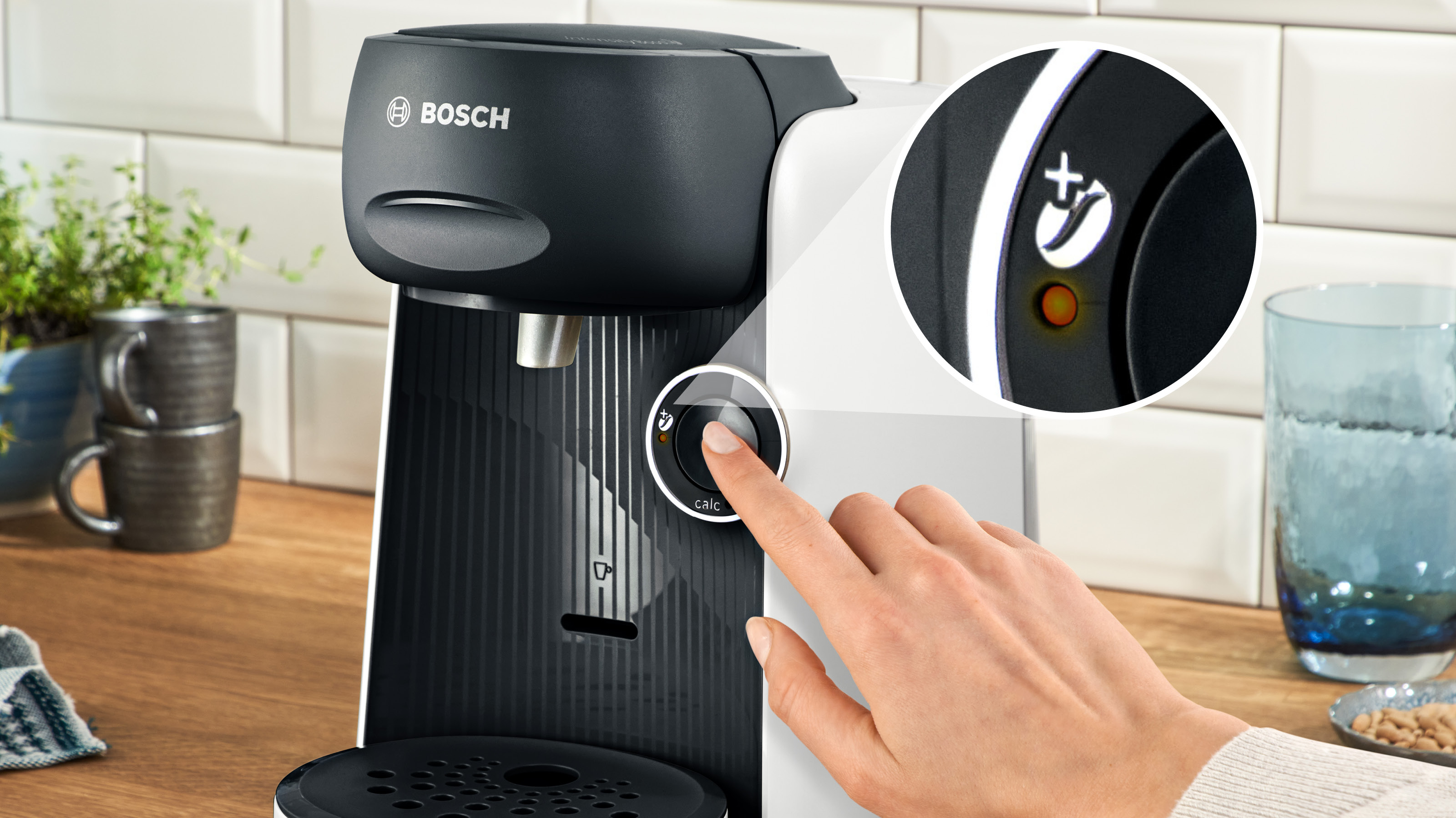 Die Hand einer Person, die einen Knopf an einer Kaffeemaschine drückt.