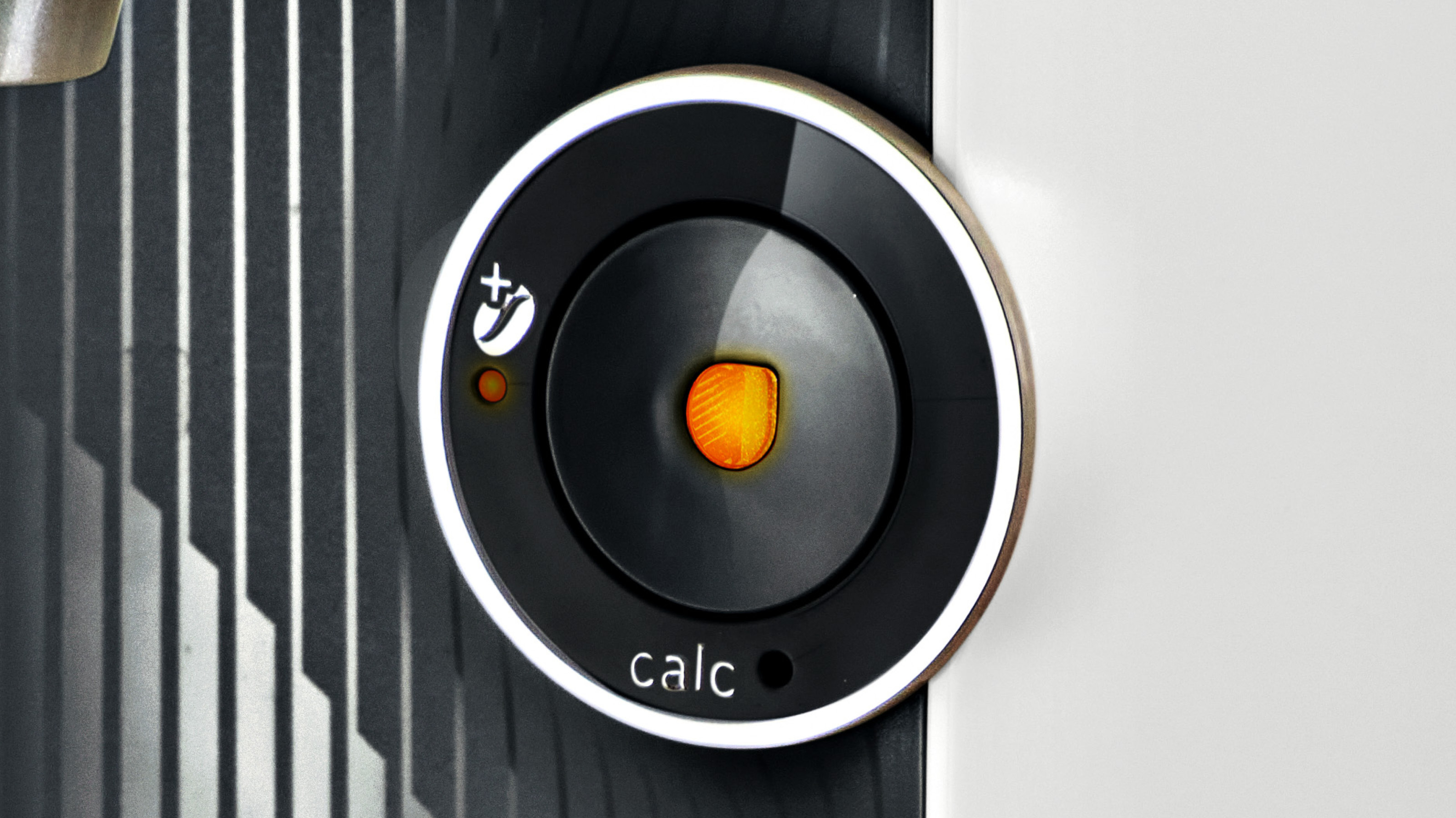 Nahaufnahme einer Kaffeemaschinentaste mit der Aufschrift 'calc' und einem orangefarbenen Licht.