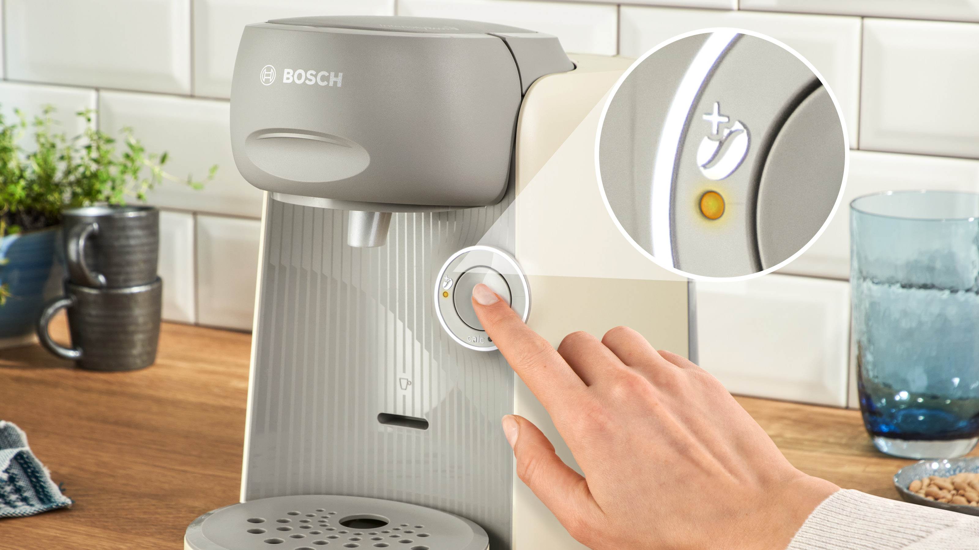 Bosch Kaffeemaschine. Hand berührt den Bedienknopf, mit Nahaufnahme des Knopfes.