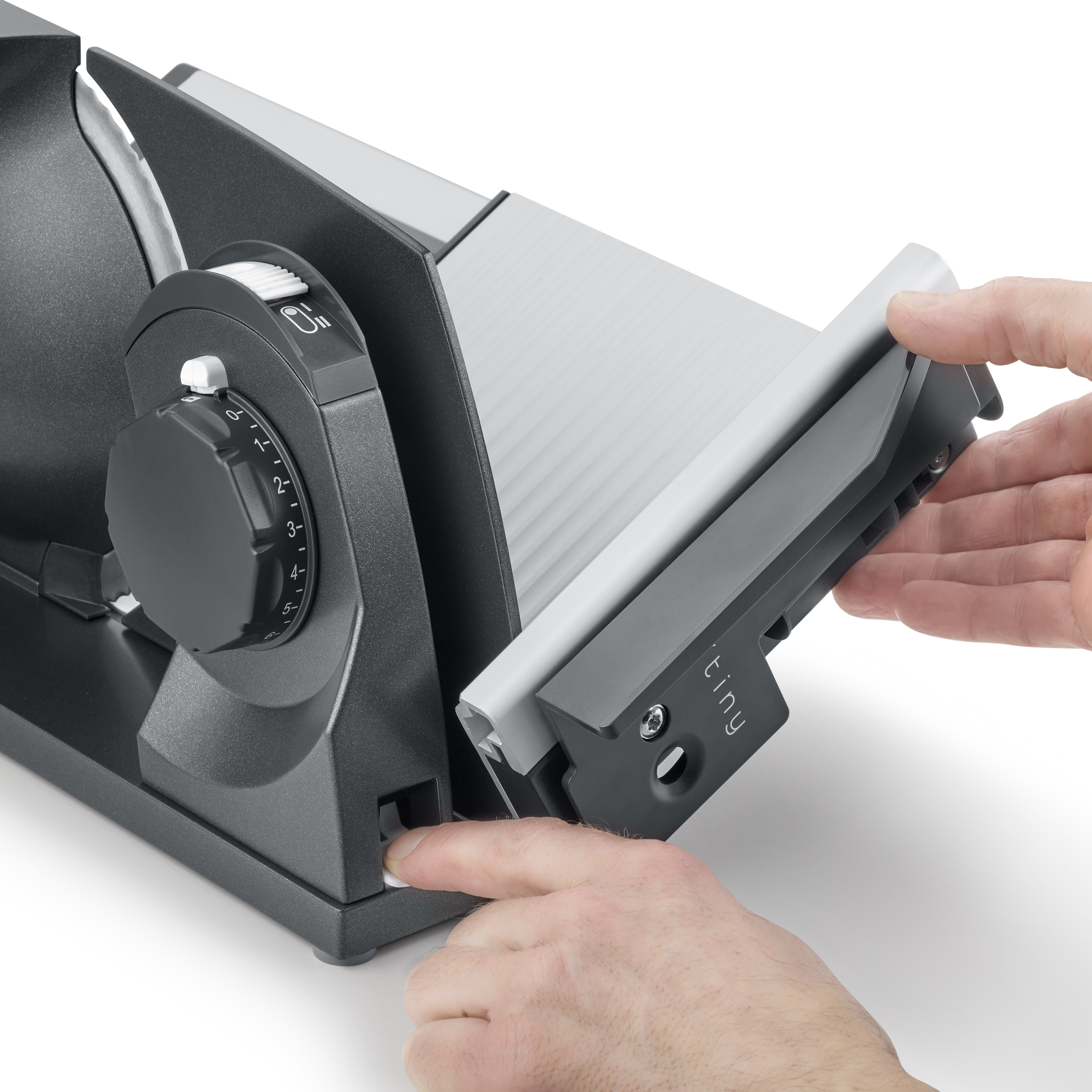 Hände benutzen einen Slicer, Klinge und Einstellrad sichtbar.