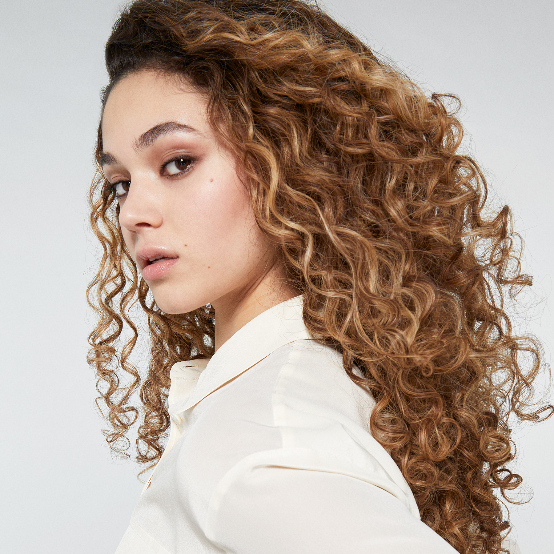 Une femme aux cheveux bouclés, regardant par-dessus son épaule.