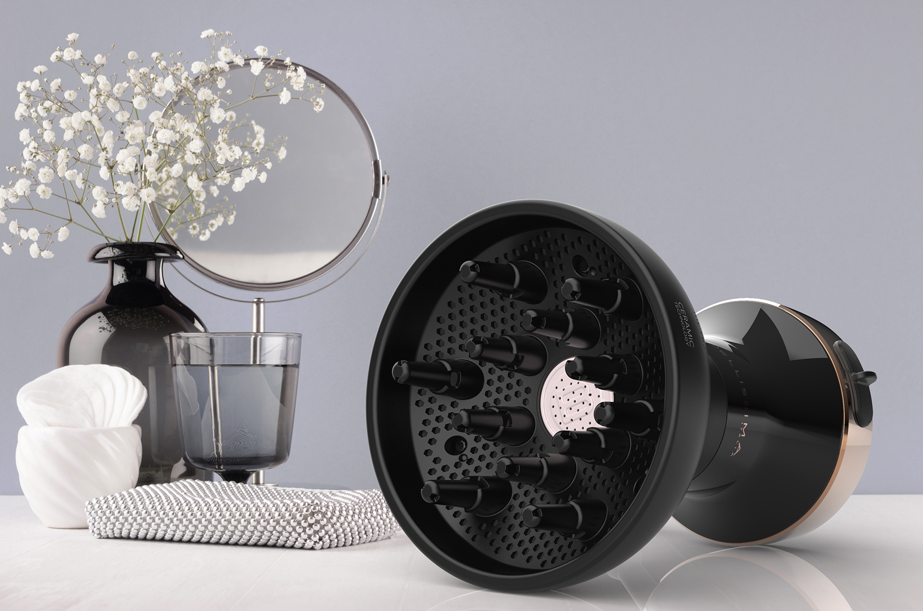 Diffuseur de cheveux, miroir, fleurs et un verre sur une surface blanche. Fond gris clair.