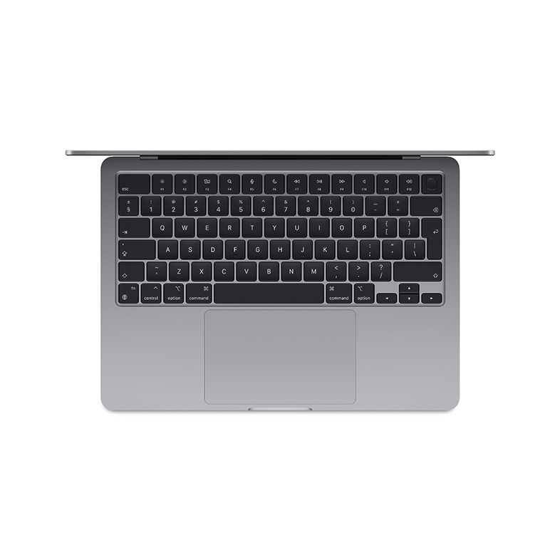 Egy személy ezüst laptopot tart, téglafal előtt, zöld hátizsákkal a földön.