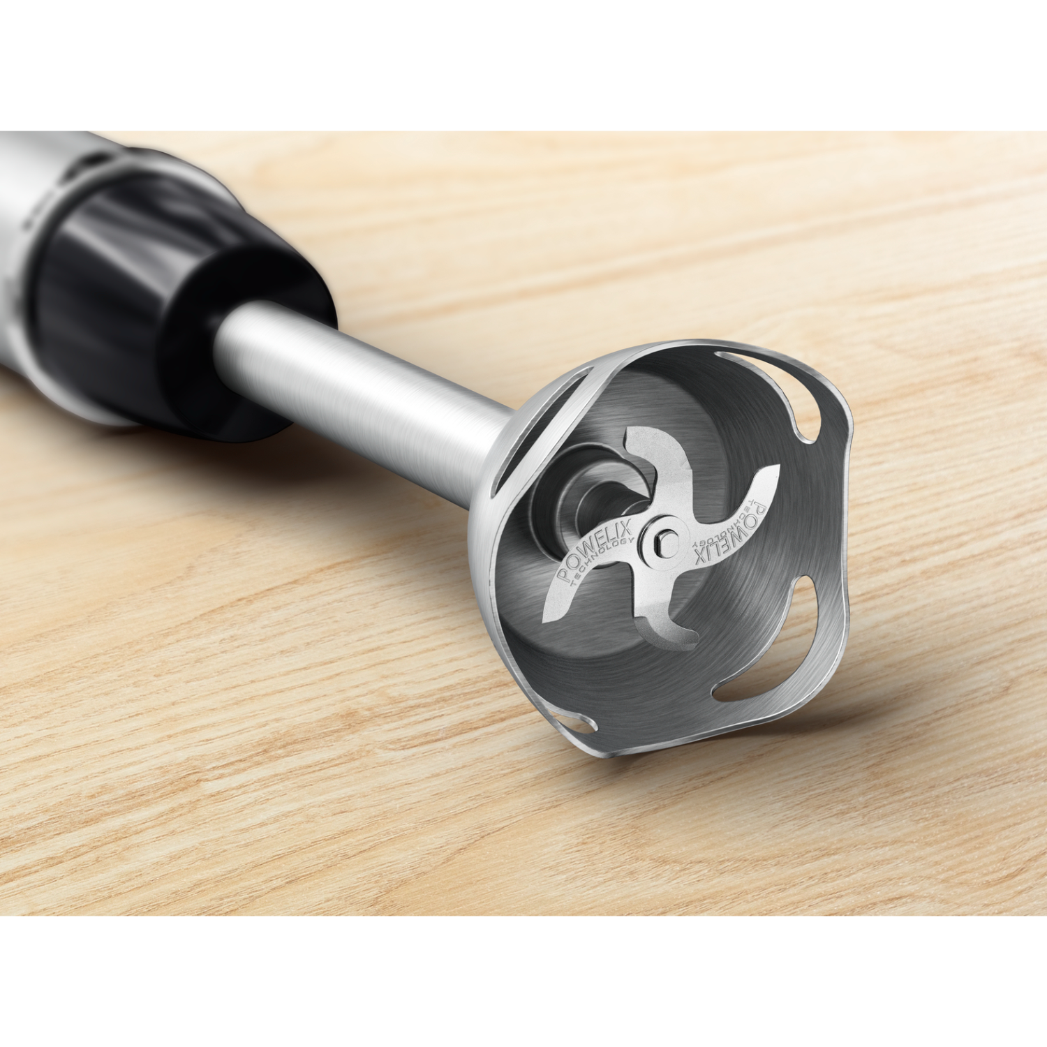 Close-up view of a stainless steel blender head with blades on a wooden surface.