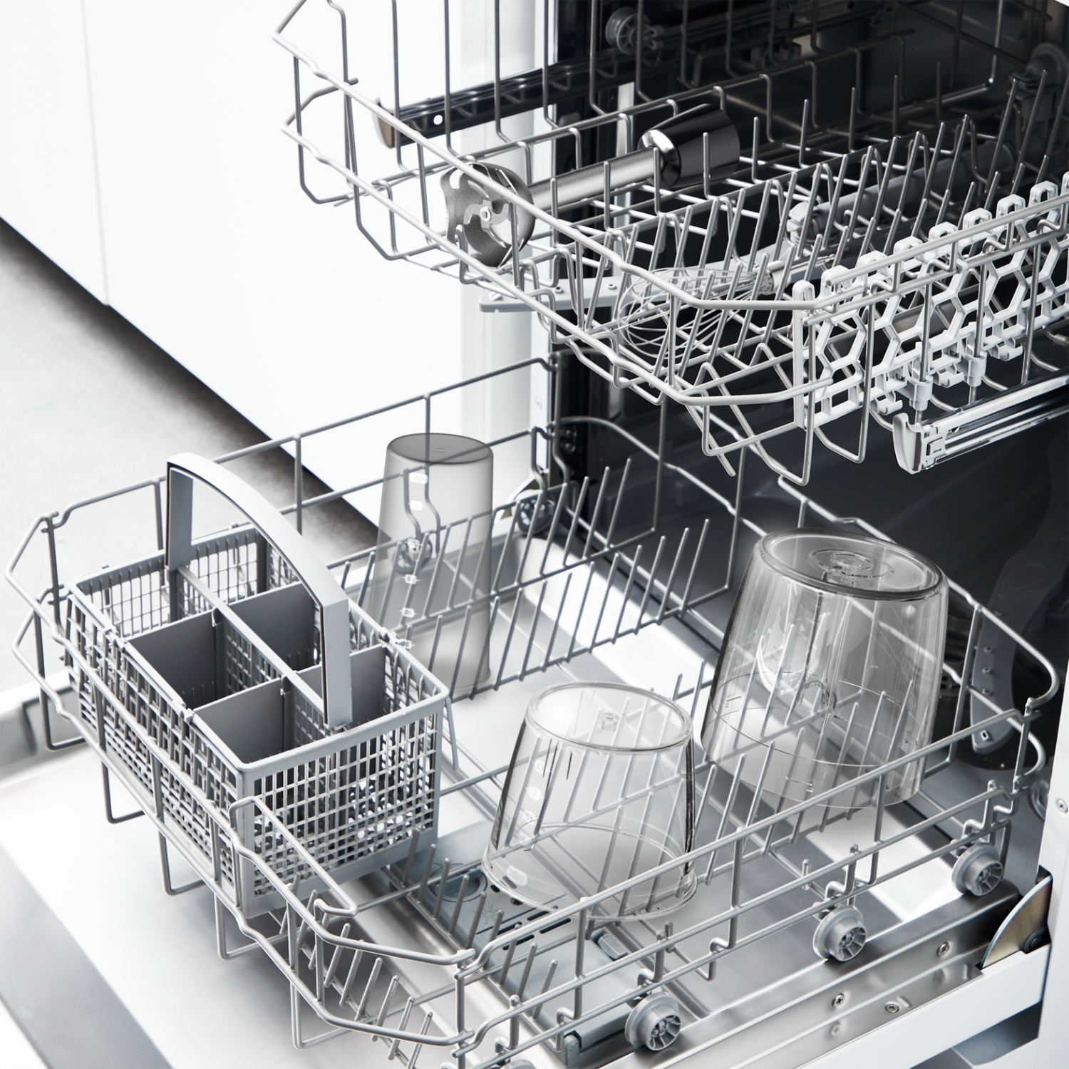 Dishwasher interior with dishes in the racks, including glasses and silverware.