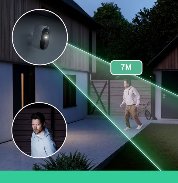 Eine Überwachungskamera an einem Haus, die ein Licht ausstrahlt. Eine Person geht in der Nähe, hervorgehoben.