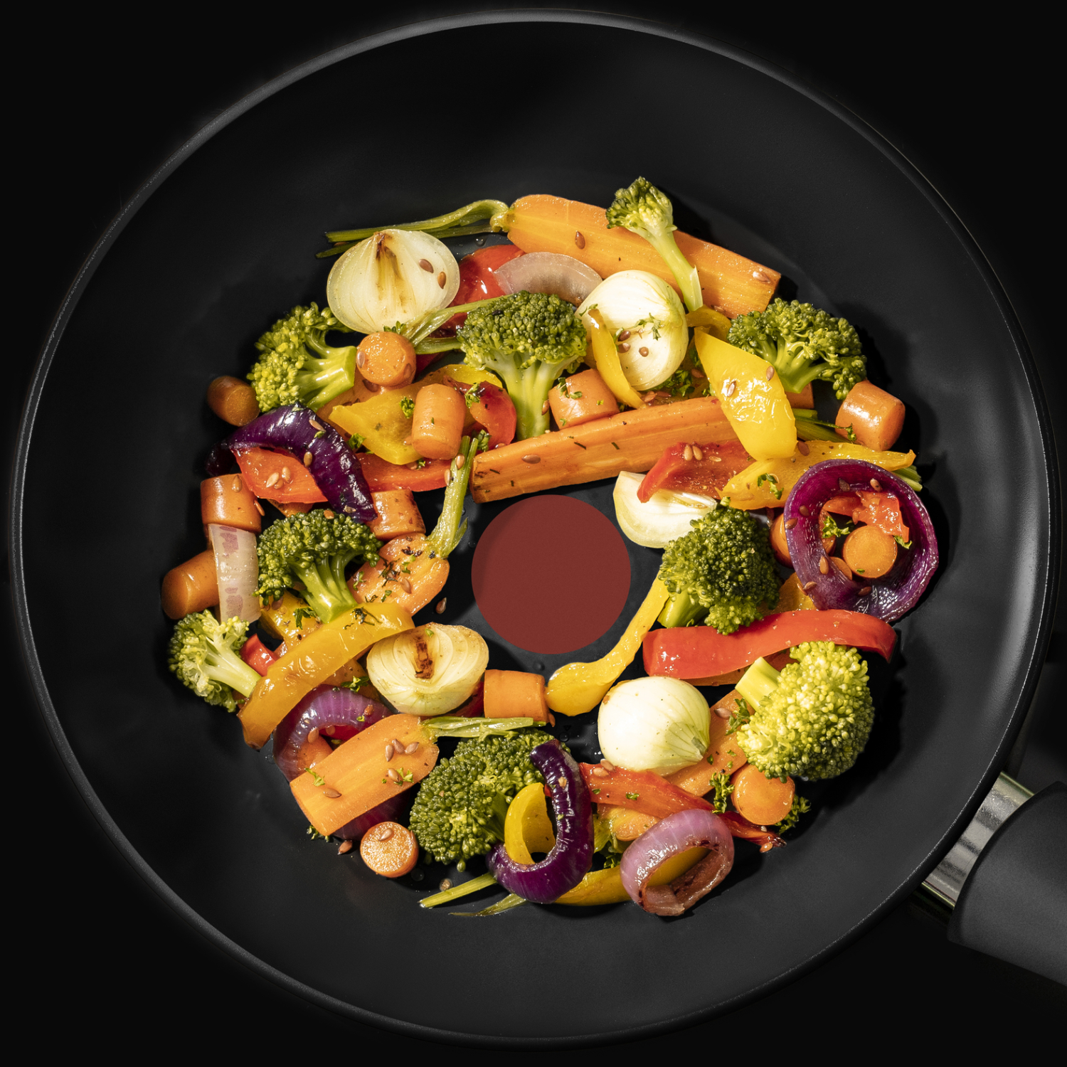 A wok with colorful vegetables is on a black surface. The vegetables are arranged in a circle.