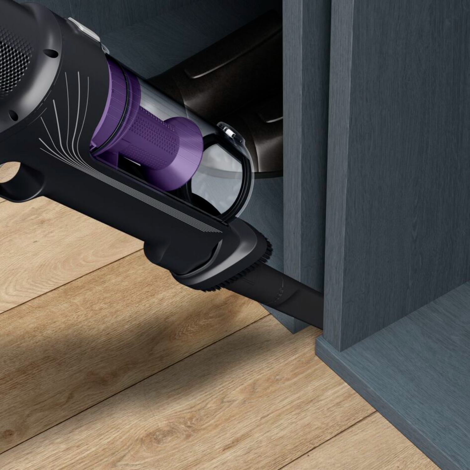 A black vacuum cleaner head cleaning a corner of a blue cabinet, on wood floor.