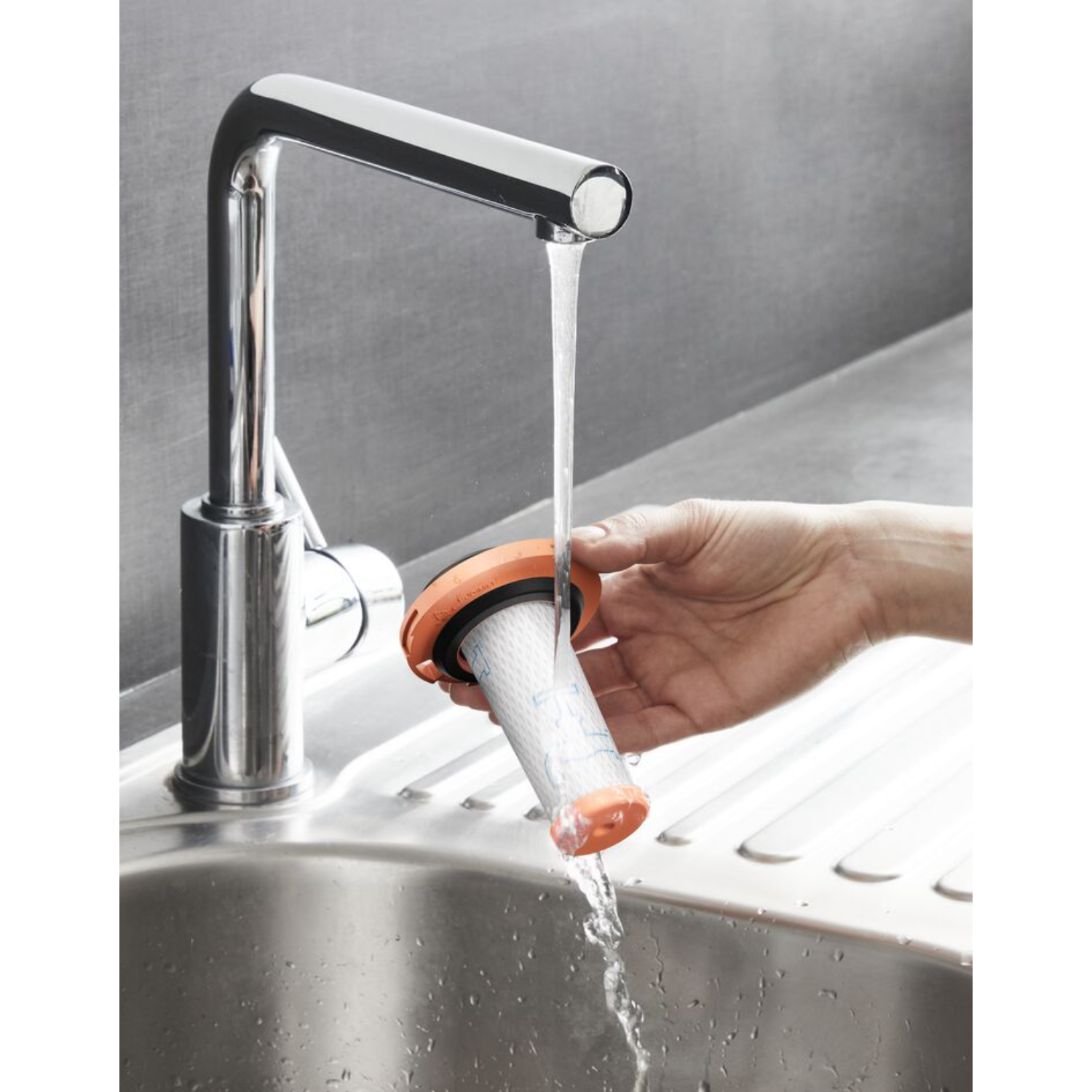 Hand rinsing a vacuum cleaner filter under running water.