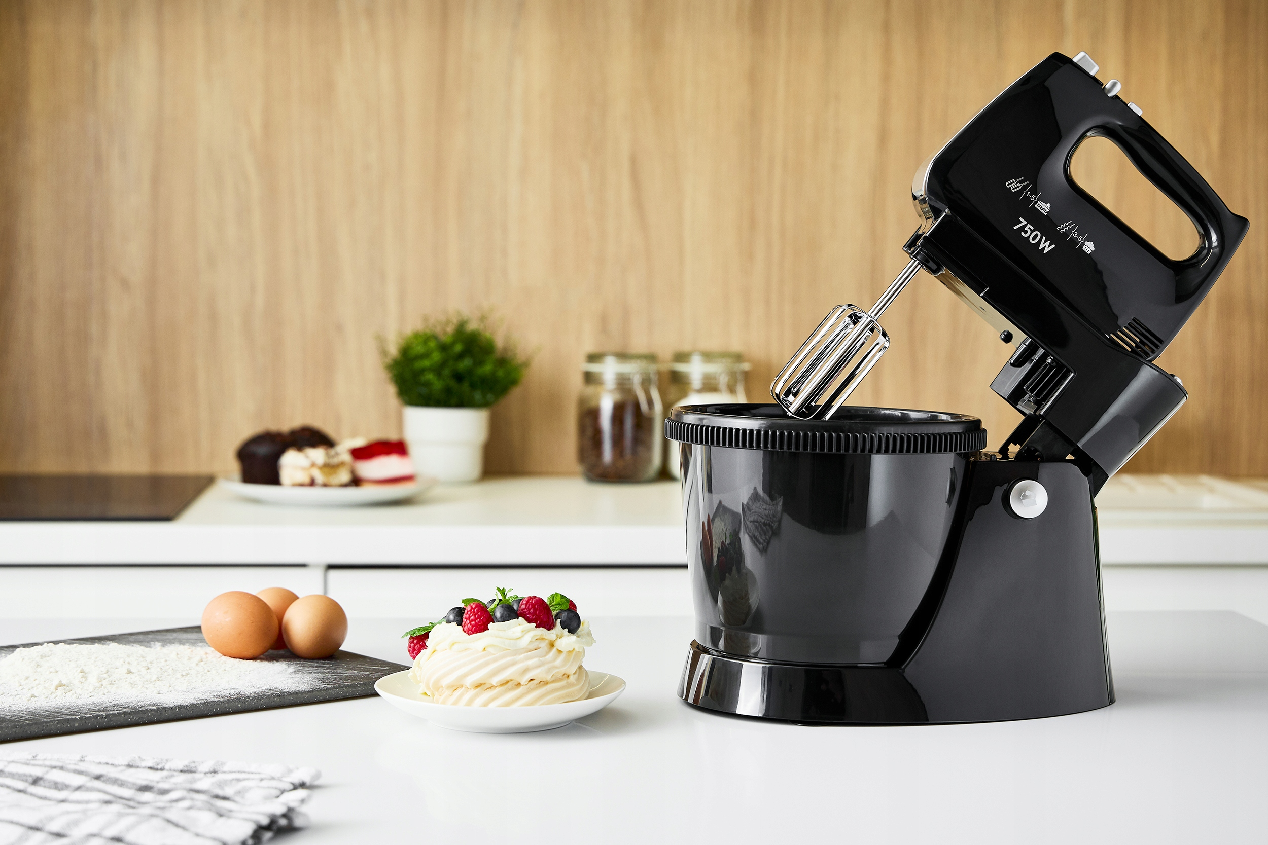 Czarny mikser z miską, obok ciasta i kilku jajek.
