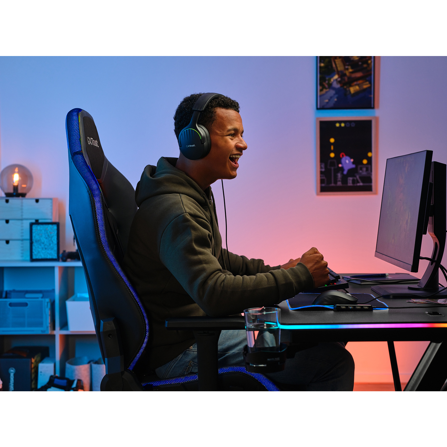 Un uomo gioca a un videogioco al computer, indossa le cuffie e siede su una sedia da gioco.