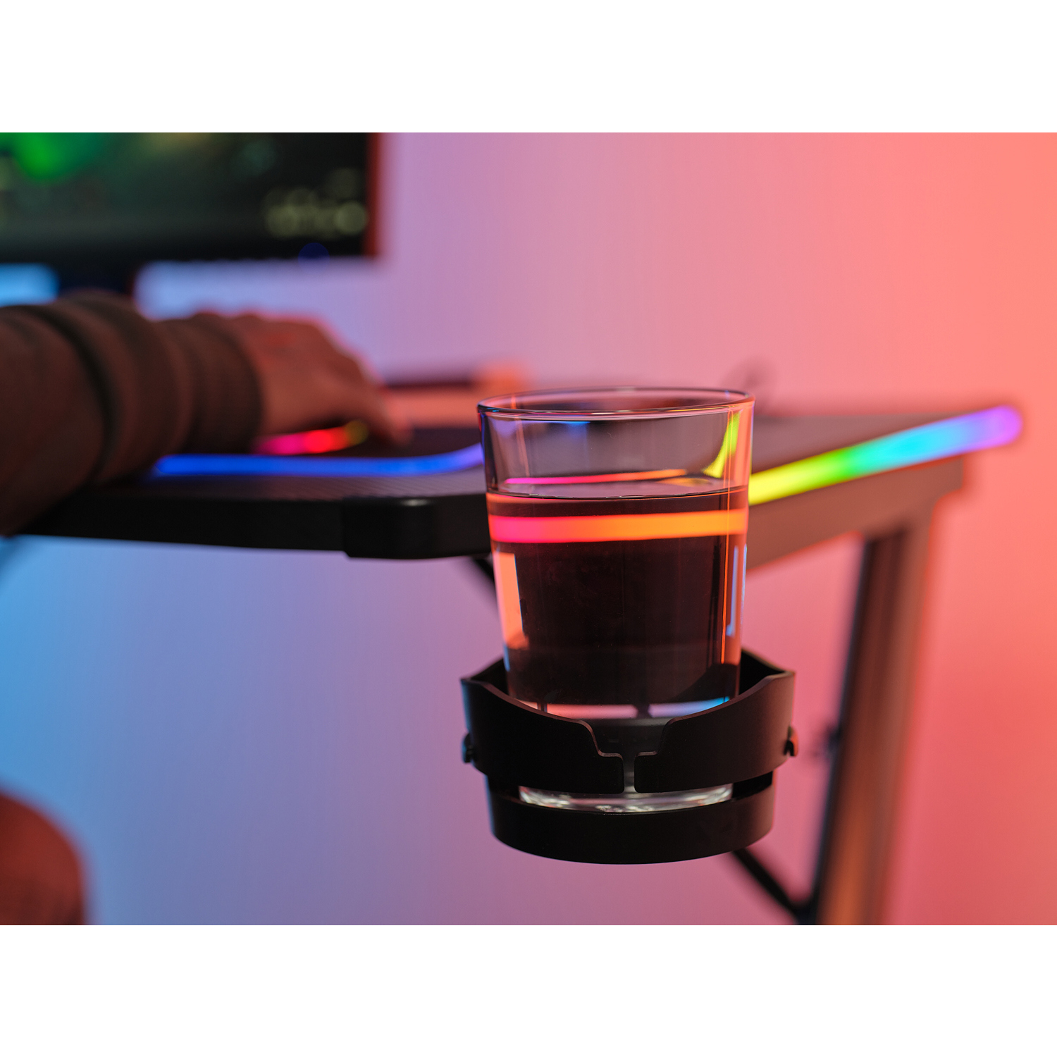 Bicchiere d'acqua in un portabicchieri su una scrivania con illuminazione RGB colorata.