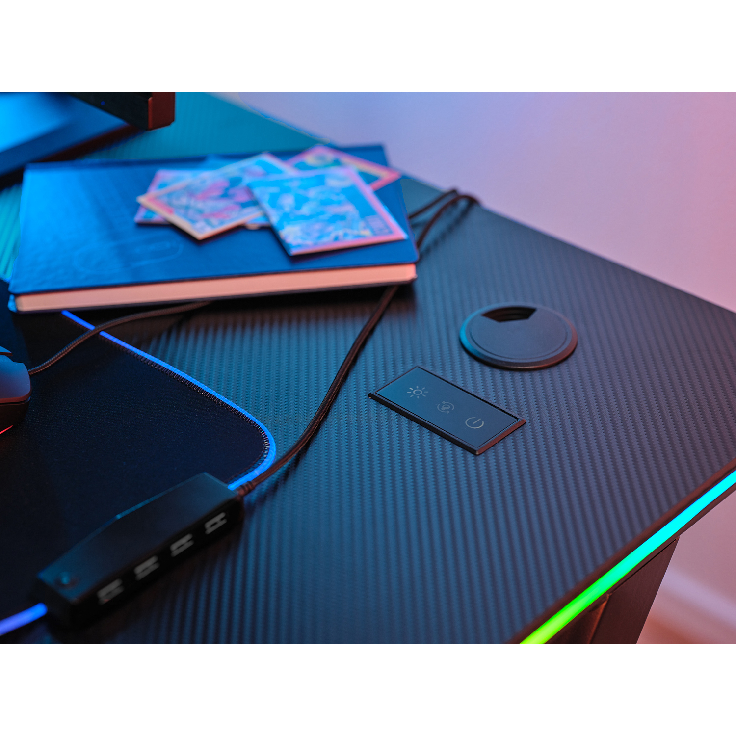 Una scrivania da gioco nera con accessori: un mouse, una tastiera, un controller e un cavo.