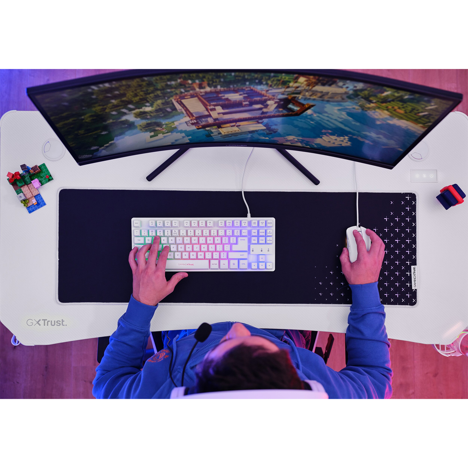 Persona che usa una tastiera e un mouse su una scrivania da gioco bianca con un grande monitor curvo.
