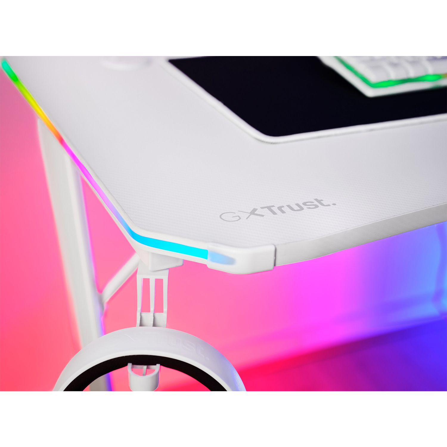 Scrivania da gaming bianca con luci RGB sul bordo e cuffie appese sotto.