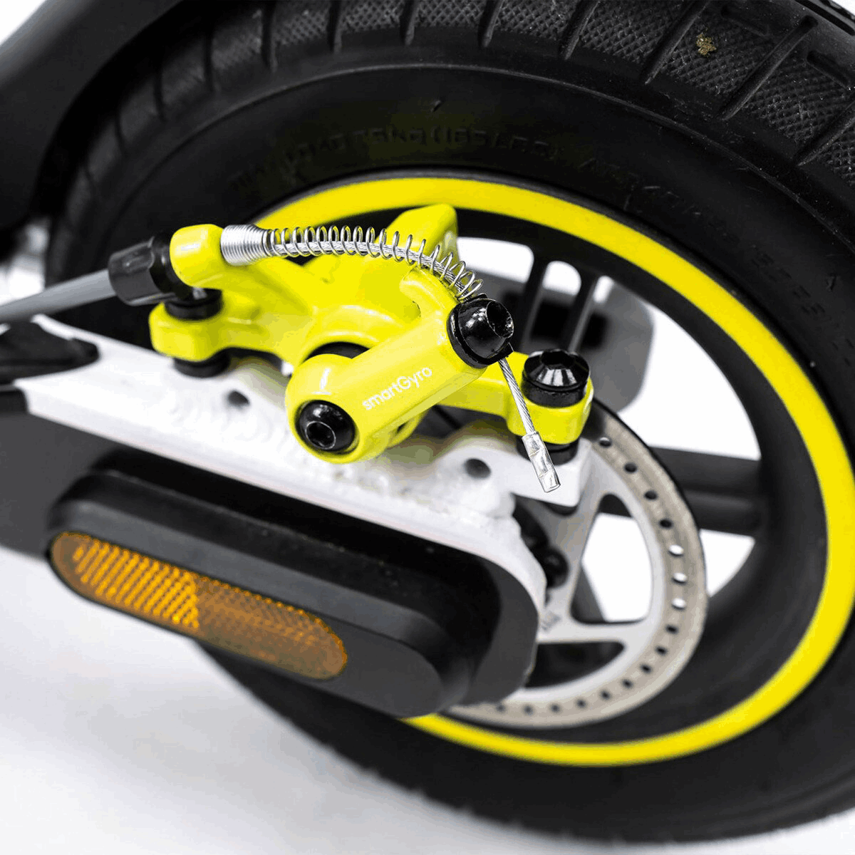 Primer plano del sistema de frenos amarillo y negro de un scooter sobre una llanta negra.