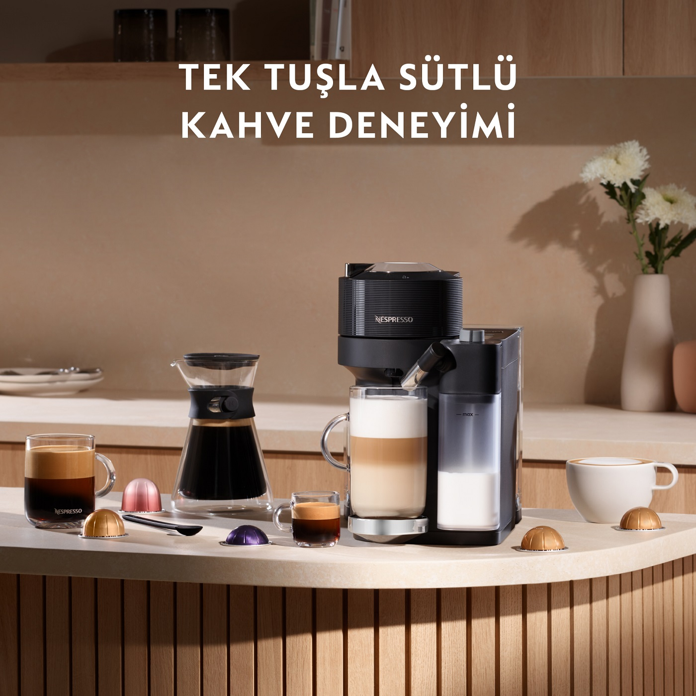Kahve makinesi sahnesi. Latte, kahve ve kapsüllerle siyah makine. Ahşap yüzey, çiçekler.