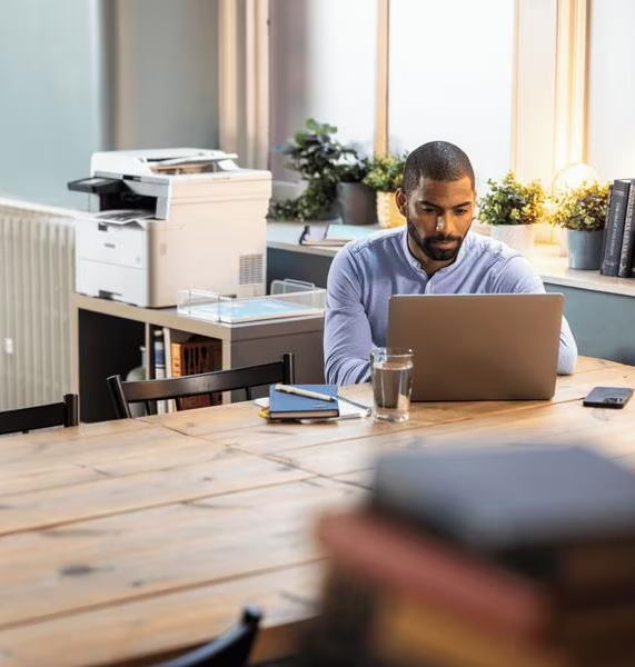 Uomo che lavora su un laptop su un tavolo di legno in un home office.