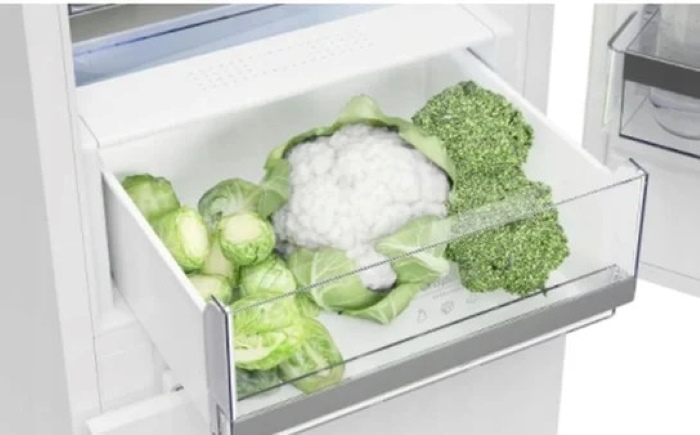 Szuflada lodówki wypełniona brukselką, kalafiorem i brokułami.